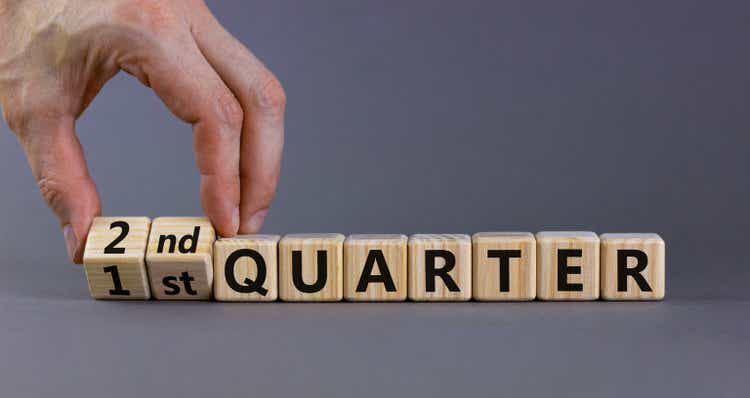 From 1st to 2nd quater symbol. Businessman turns cubes and changes words "1st quater" to "2nd quater". Beautiful grey table, grey background. Business, happy 2nd quater concept, copy space.