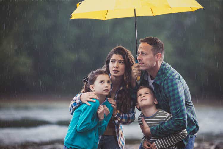Worried family under the umbrella on rainy day in nature.