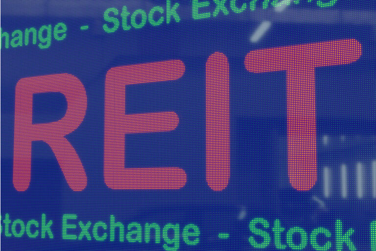 REITs (Real Estate Investment Trusts) on a blue LED screen framed by the text stock exchange in green.