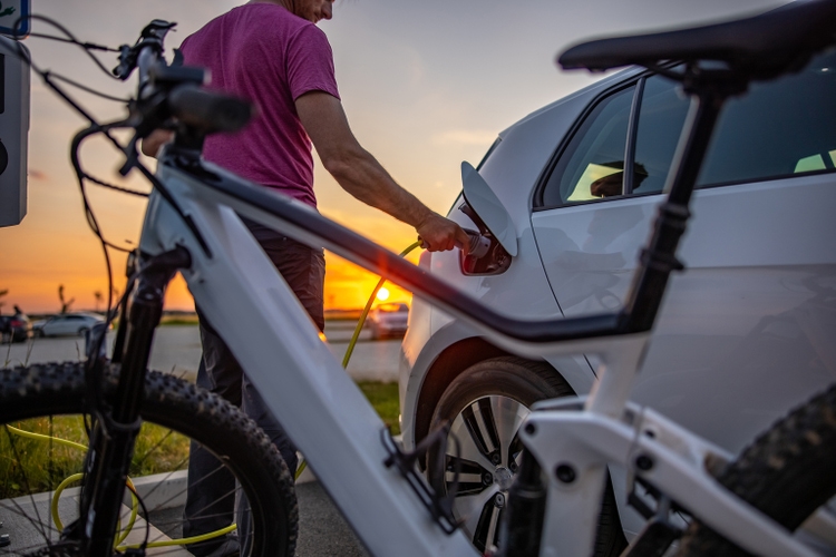 Man inserting electric plug into car for charging