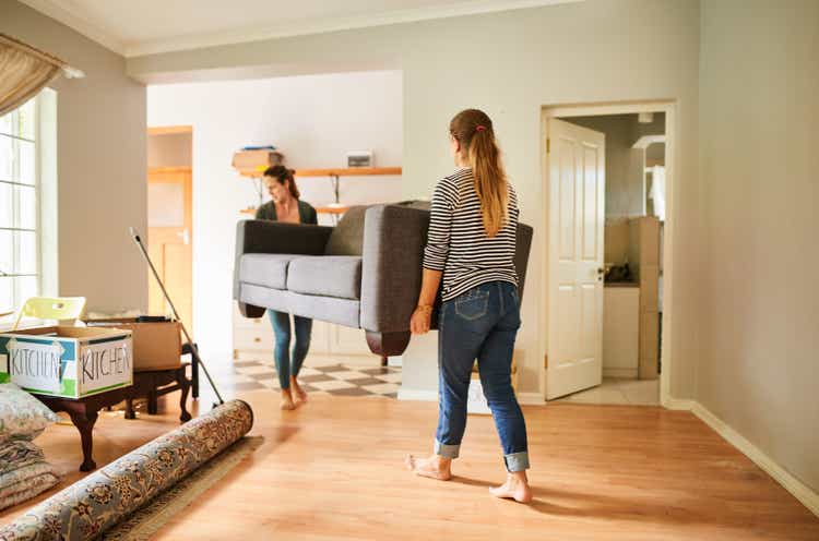 Female friends carrying a sofa out of a house on moving day