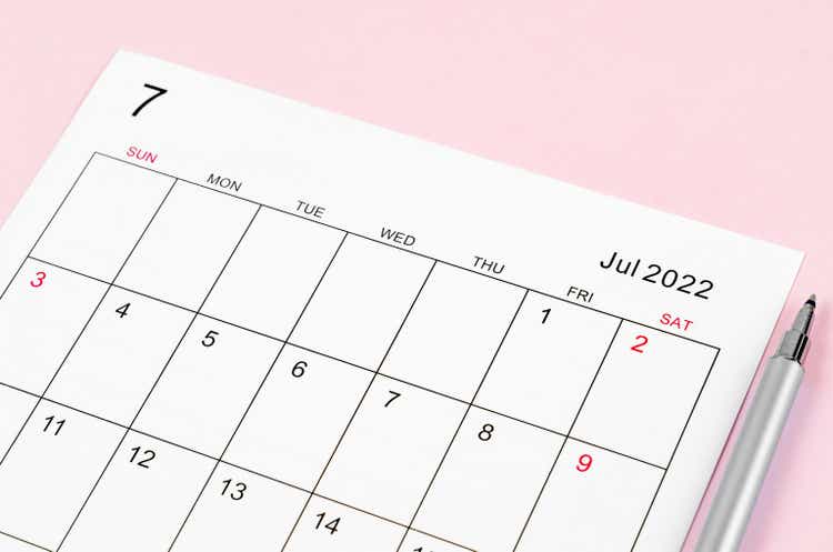June 2022 calendar sheet with pen on pink background.