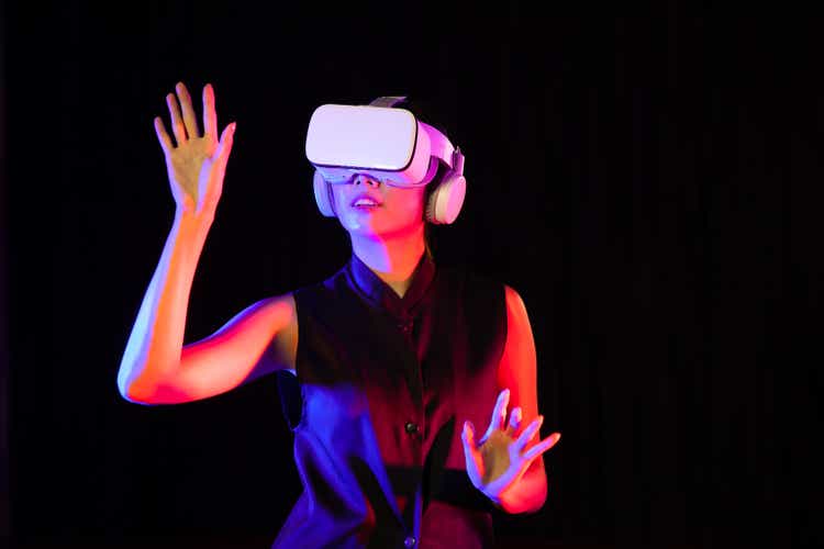 Asian woman in vr glasses with virtual reality headse. she looks like to touching something on screen, Metaverse Concepts