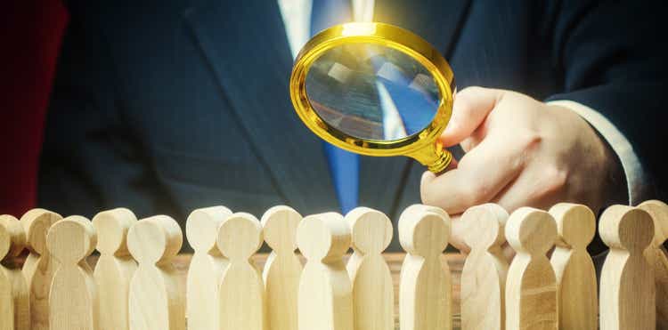 Businessman is studying a crowd of people with a magnifying glass. Hr search candidates for work, staff recruiting. Society, demographic. Market and customers research. Citizens electorate. Sociology