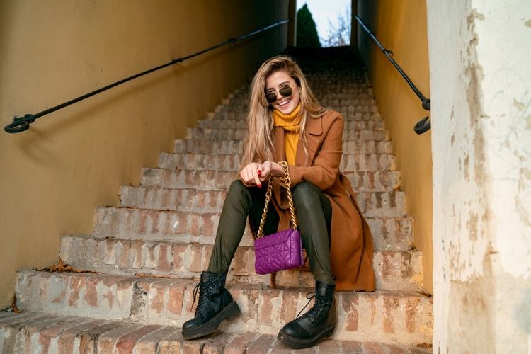 Blonde girl in coat sitting on the stairs and laughing