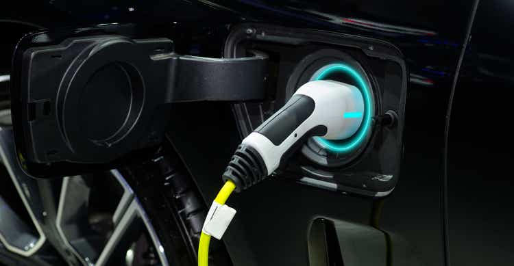 Close-up hand grip plug of industrial electric charging machine connected with socket charge on black modern car for rechargeable battery, zero emission vehicle (<a href='https://seekingalpha.com/symbol/ZEV' title='Lightning eMotors, Inc.'>ZEV</a>) and green energy for smart life