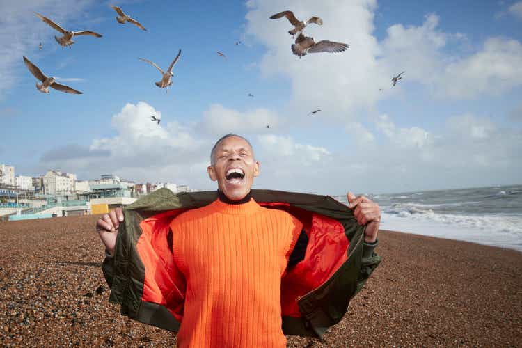 Senior man screaming while birds flying at beach
