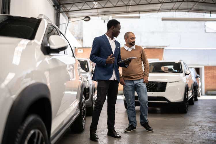 Salesman showing a car to a customer in a car dealership