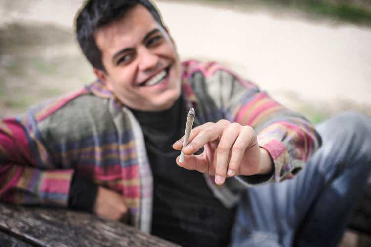 Close-up view of relaxed smiling happy man smoke ganja joint