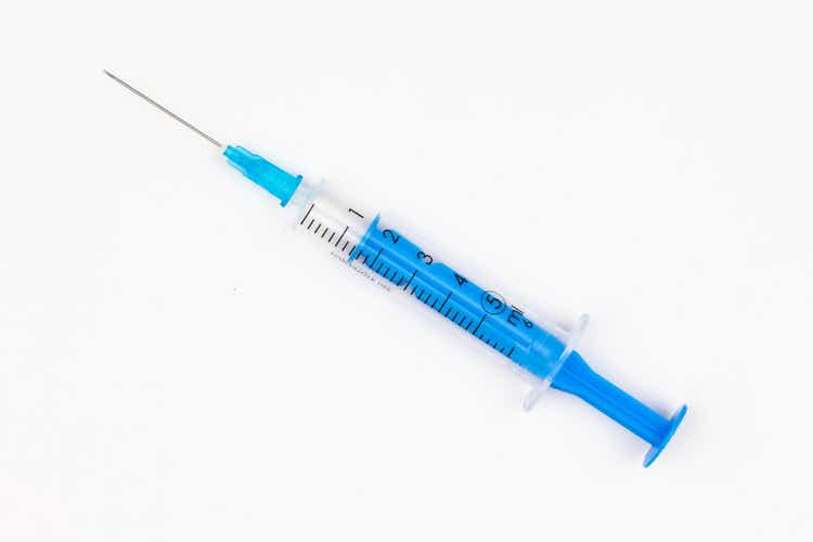 Blue medical disposable syringe for injection on a white background. Medical instrument for vaccination. 5 ml syringe for COVID-19 vaccine. Medical equipment. Isolated. Top view. Close-up