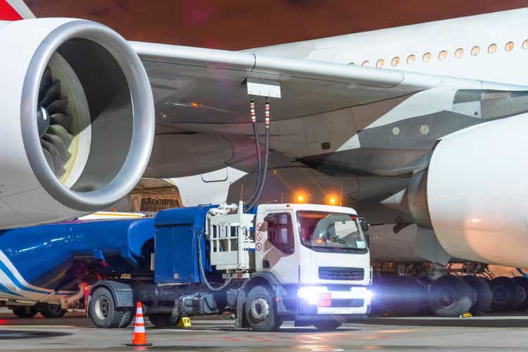 A truck with a tank of kerosene of aviation fuel connected to the fuel tanks of a large aircraft airliner, refueling service of a night flight