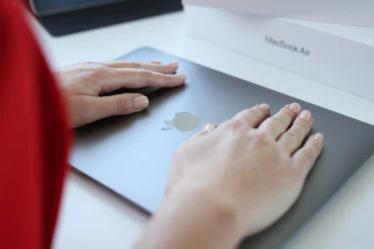 Woman hand rests on top cover of Apple Macbook Air