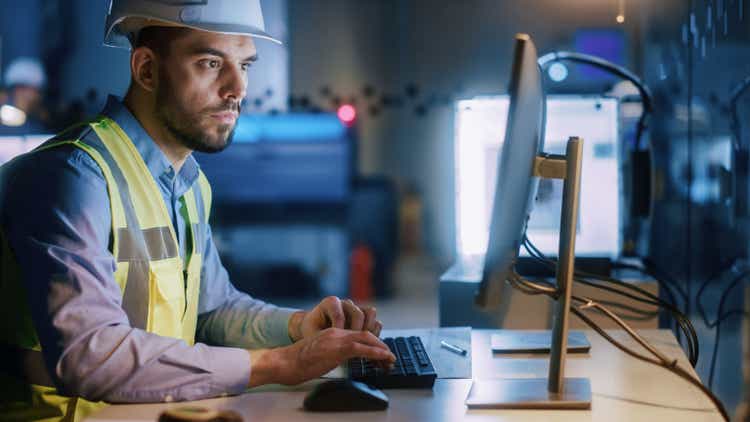 Electronics Design Factory: Portrait of Handsome Male Engineer Wearing Safety Vest Working on Computer, Developing Industrial Microchips, Semiconductor, Manufacturing Processors.