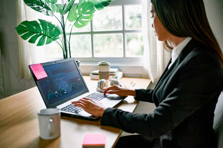 Young business woman working on laptop computer inside bank office - Focus on screen
