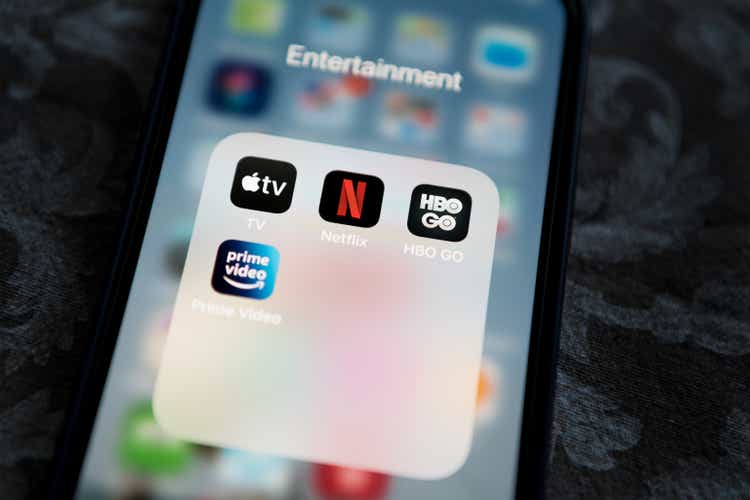 Netflix application icon among Apple TV+, Amazon Prime Video, and HBO GO in Entertainment Folder on Apple iPhone 12 Pro MAX screen close-up. Popular streaming services.