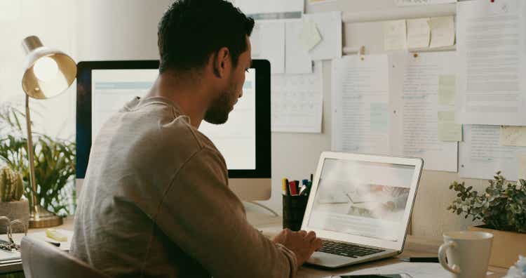 Shot of an unrecognisable businessman sitting alone and using his laptop while working from home