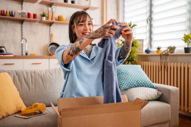 Woman unpacking package with new t-shirt at home