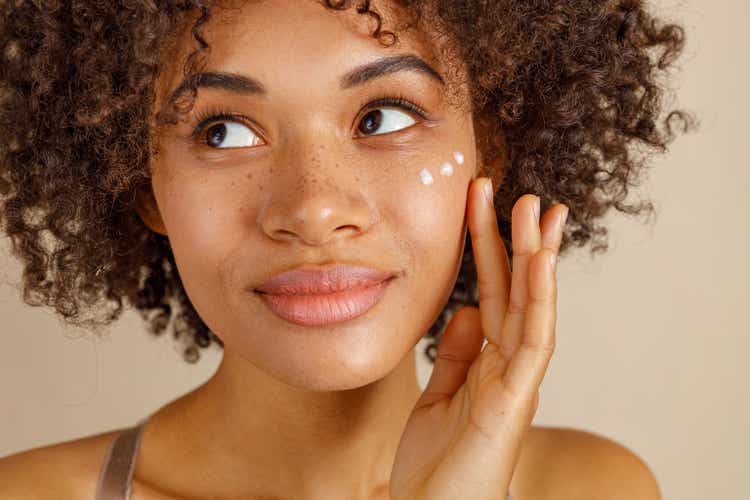 Cute lady using cosmetic product in studio