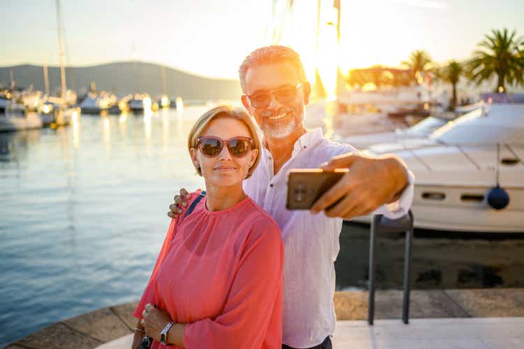 Mature couple in port taking photo with smart phone