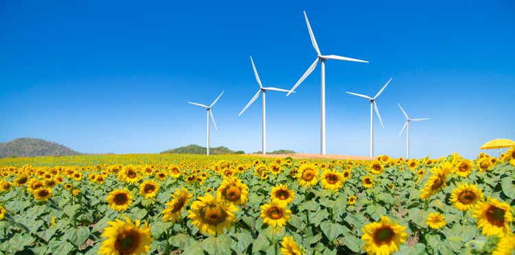 vista grandangolare di un campo di girasole in una giornata limpida e turbina eolica sullo sfondo blu del cielo.