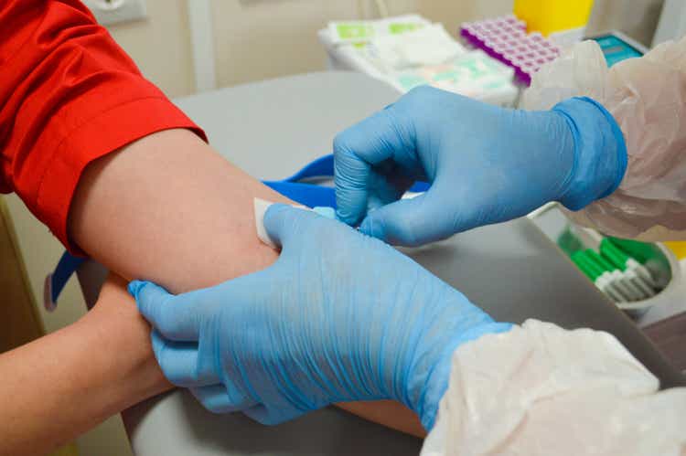 Doctor using syringe takes blood from patient arm