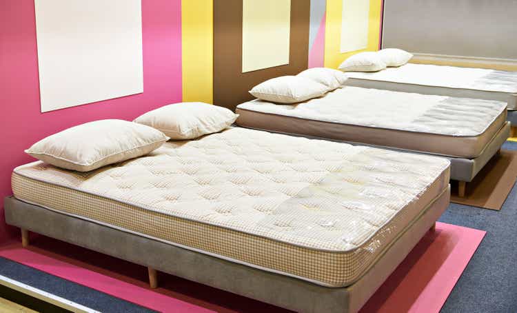 Modern bed with mattresses and pillows in store