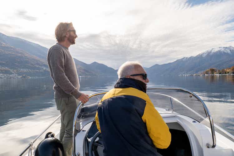 Father and son on pilot boat enjoy lake in Autumn