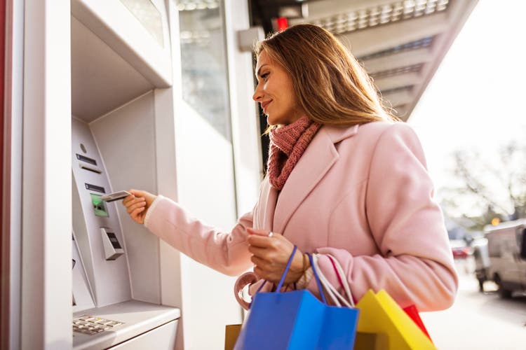 Young woman withdrawing with credit card at ATM