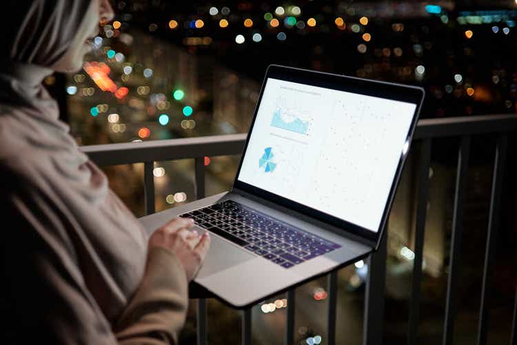 Young female economist in hijab analyzing financial graph