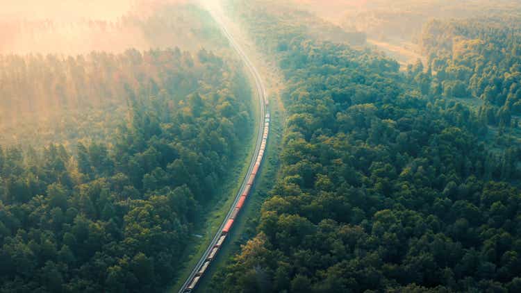 Cargo Train rides through the forest in the fog at dawn on a summer morning - aerial shot