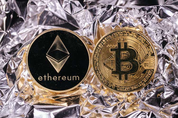 Kriptovaluta Ethereum i bitcoin, fizički novčići ispred apstraktne pozadine.