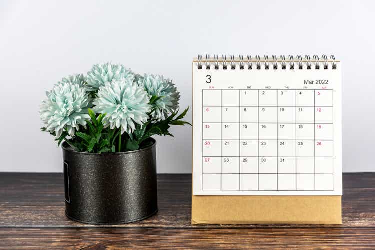 March 2022 calendar date with flowers on black vase on the rustic wooden table.
