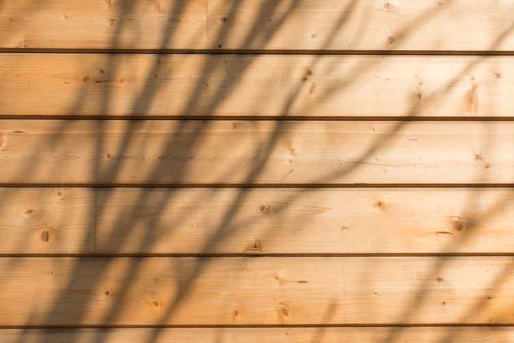 The facade of the house is made of new horizontal wooden boards. Wooden texture. With sunlight and shadows