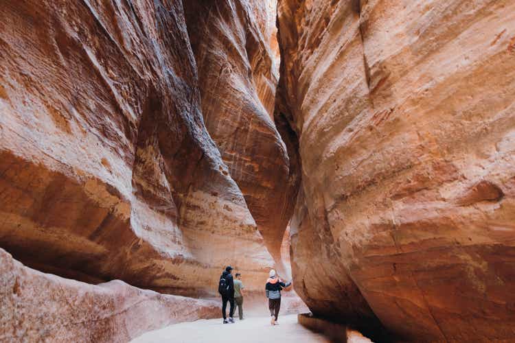 Friends travelers exploring the ancient world of Petra in Jordan walking inside the canyon