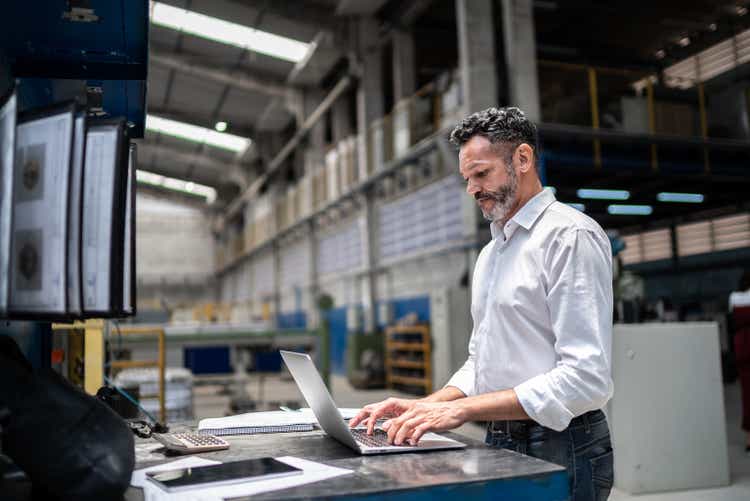 Mature businessman using laptop in a factory