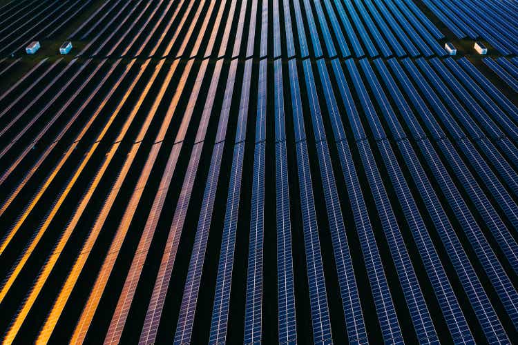 Drone view over a field of solar panels at sunset