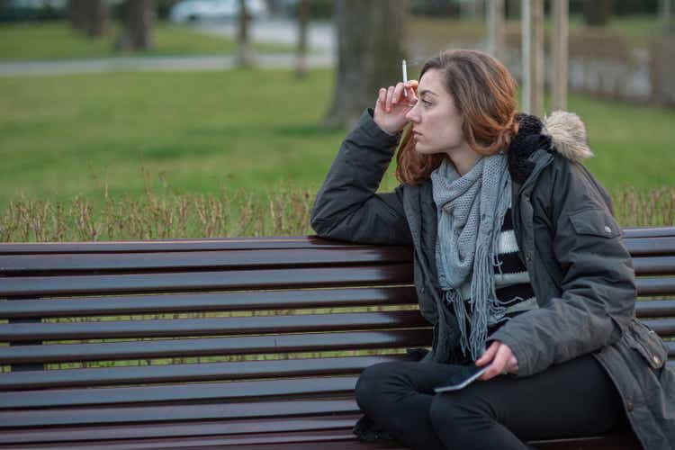 Depressed girl smoking on a bench