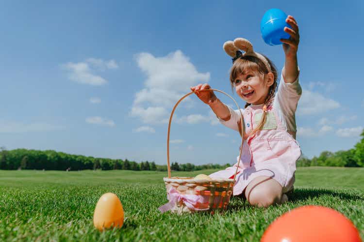 Little girl picking up and putting toy eggs in a basket