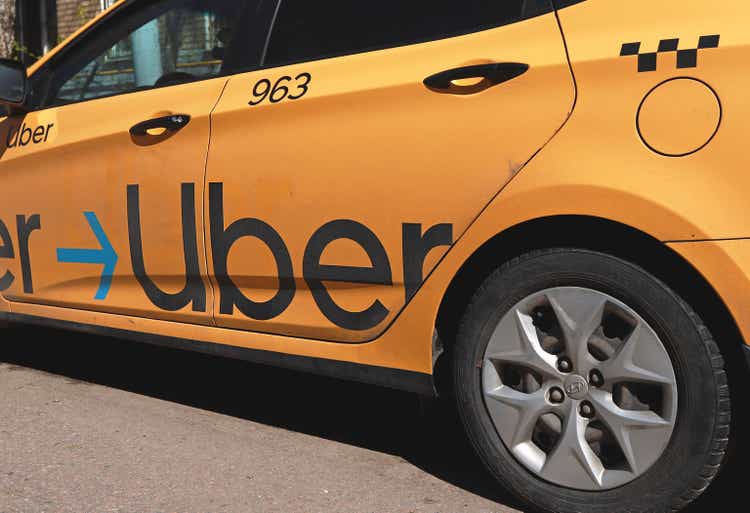 Moscow, Russia: Yellow taxi with Uber logo on the street. Yellow taxi cab with checker pattern. Uber taxi cab.