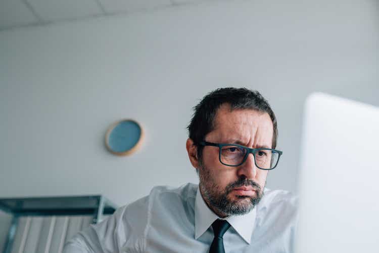 When stock prices drop, worried businessman looking at laptop as money disappears from account