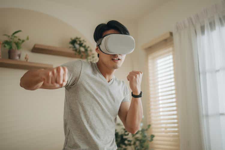 Sport man boxing in VR headset training for kicking in virtual reality at home