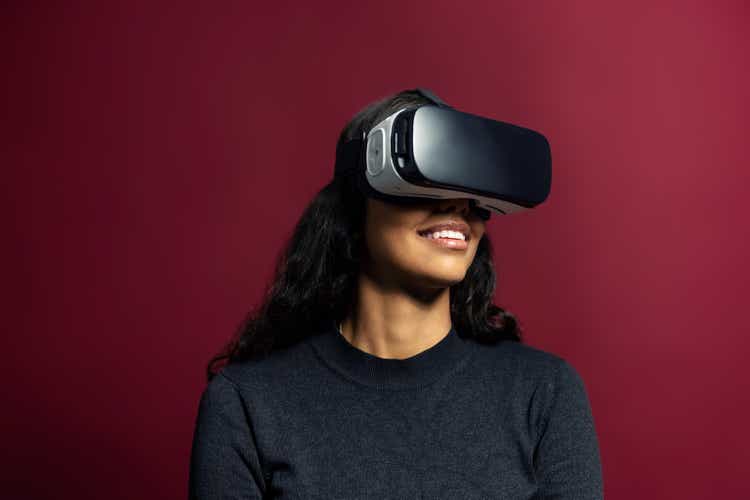 Young woman using vr glasses on red background