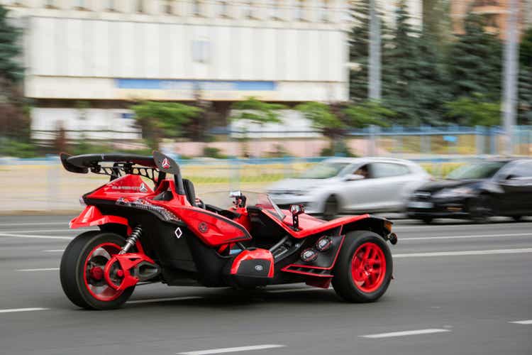 Photo without focus. Unique red tricycle Polaris Slingshot SL in motion on the road