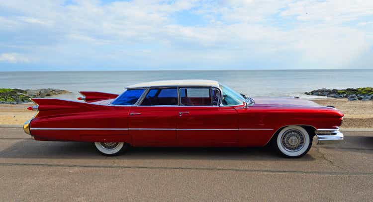 Klassischer roter 4-türiger Cadillac-Motorwagen aus den 1950er Jahren, der an der Strandpromenade geparkt ist.