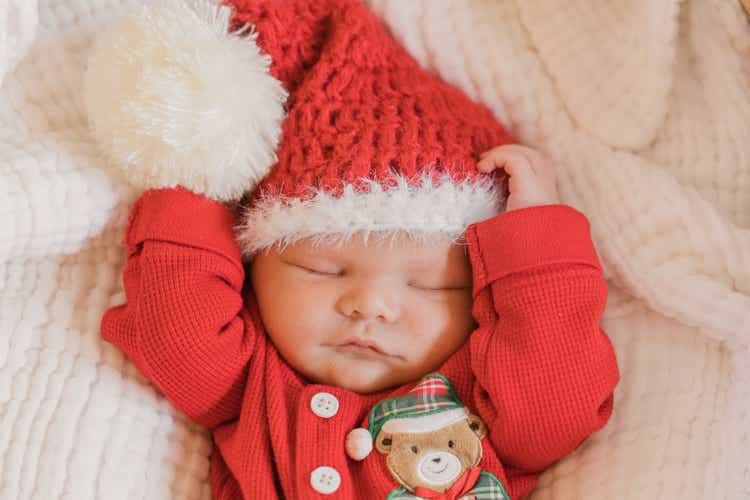 Newborn Baby Boy Dressed in a Cozy Red Christmas Outfit Asleep Snuggly in His Moses Basket