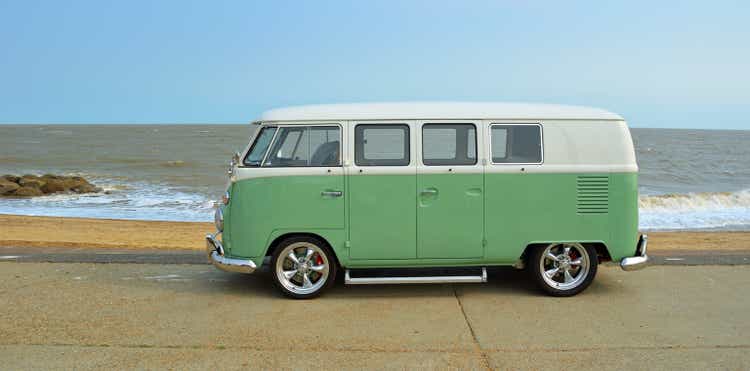 Classic Green and white VW Camper Van parked on Seafront Promenade. beach and sea in the background