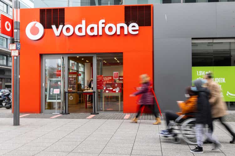 facade and shop window of the Vodafone store with passengers in motion blur in front. Vodafone is a British multinational telecommunication company
