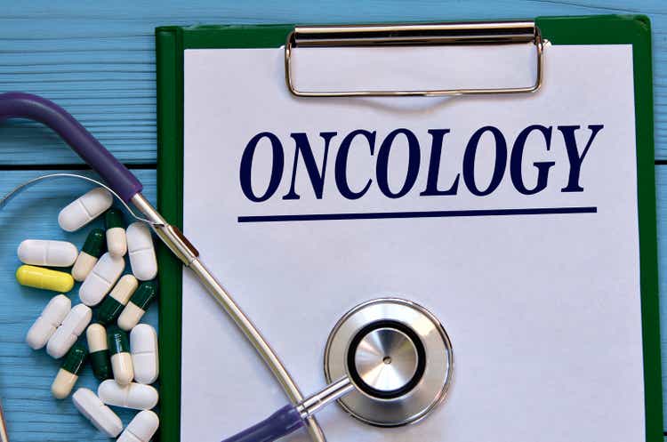 ONCOLOGY - word on a white sheet on a blue background with tablets and a stethostecop