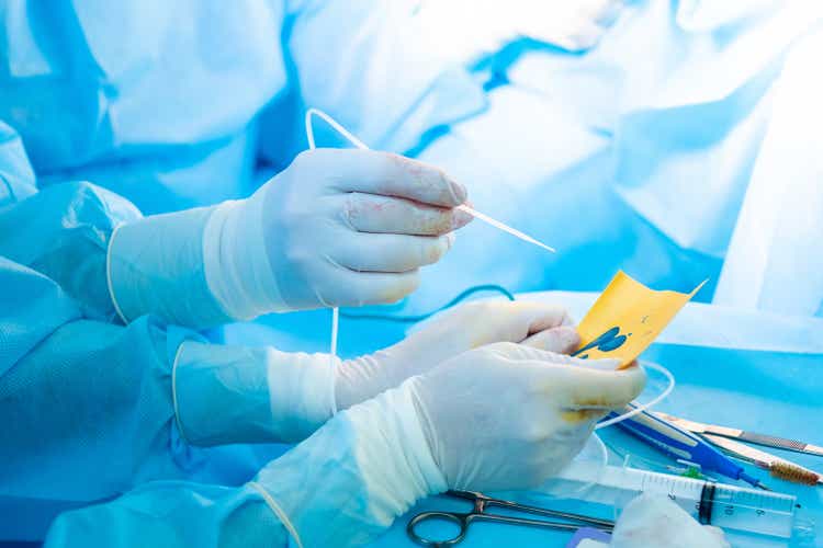 The surgeon"s hand in a sterile glove holds a fibrin glue dispenser.