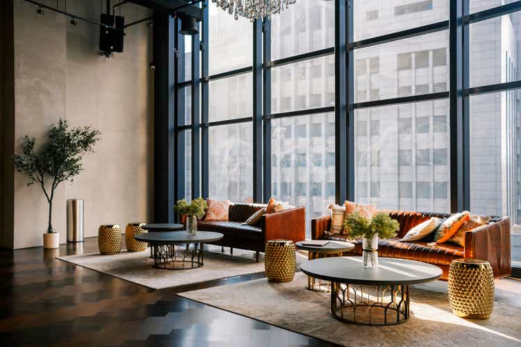 lounge with sofa, carpet and coffee table against window with city view lobby area